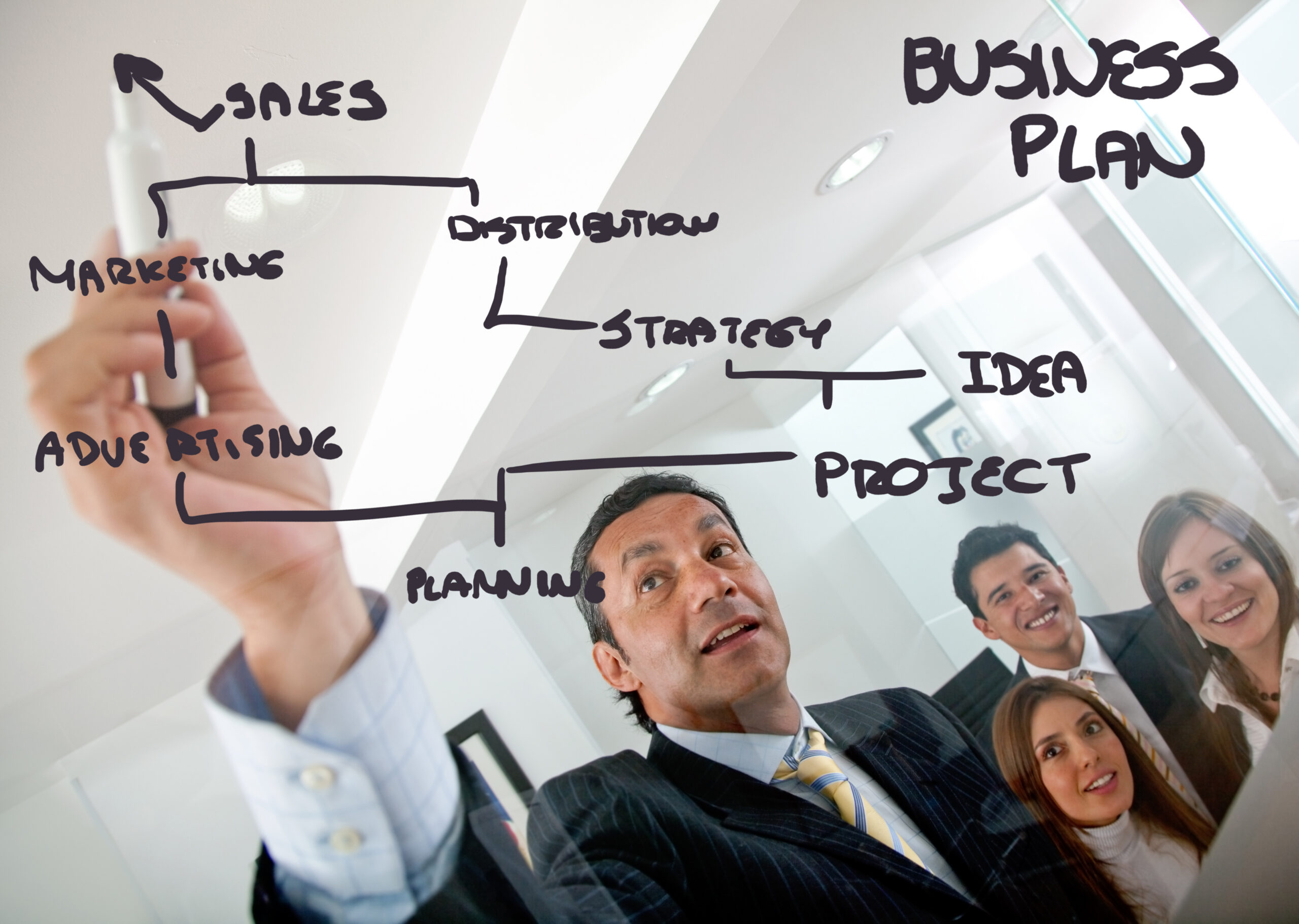 A business leader drawing business development strategies on a clear board.