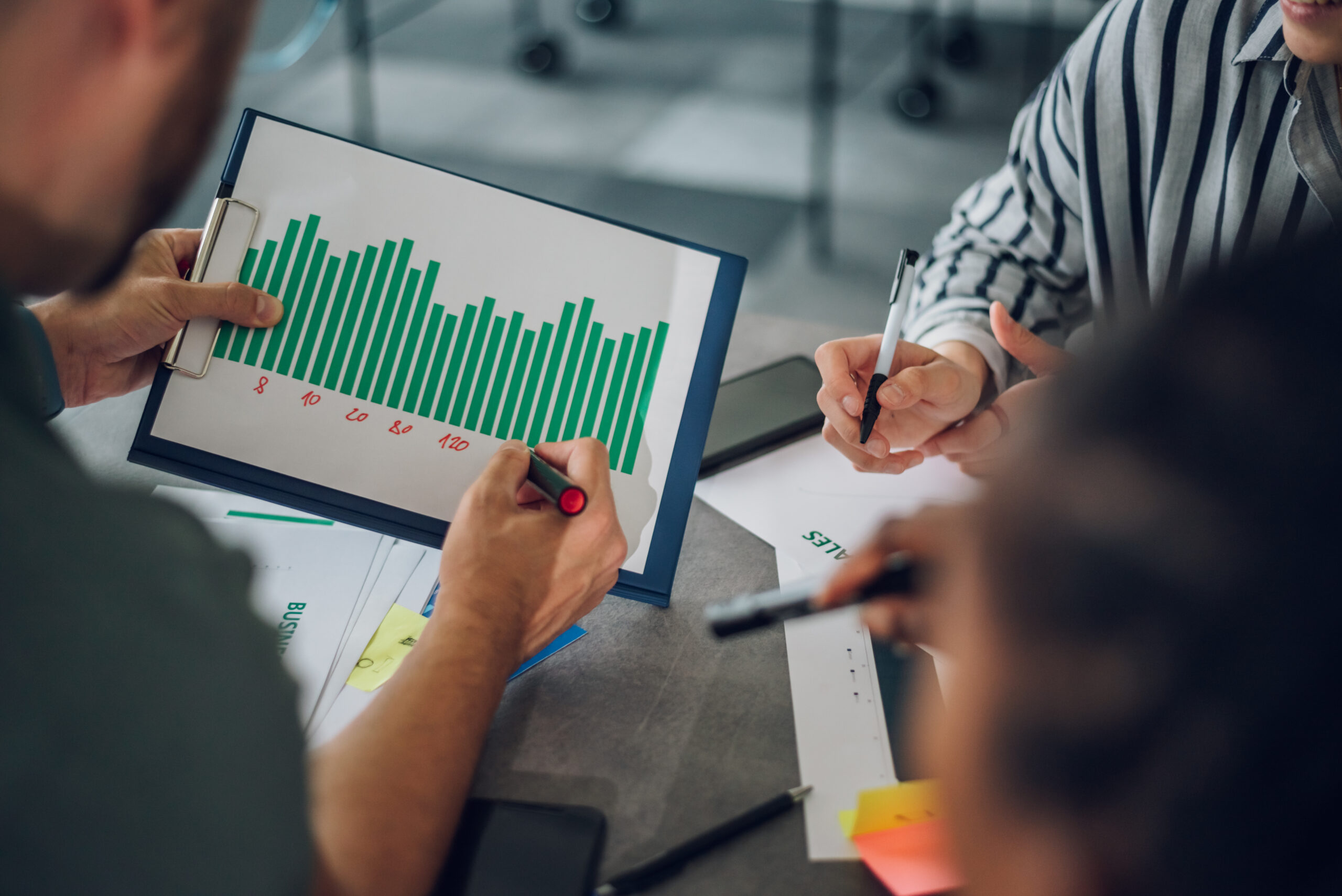 Three people are gathered around a table reviewing buying patterns.